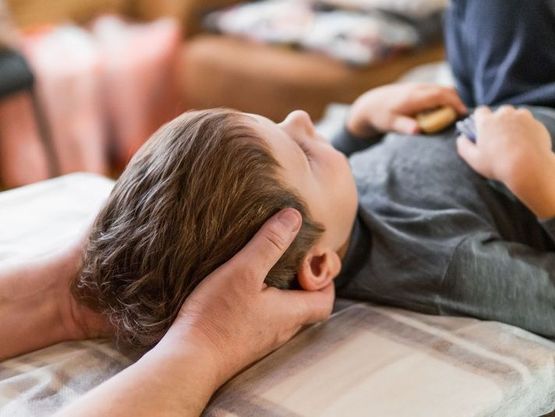 sujetando la cabeza de niño tumbado